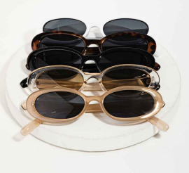 Assorted oval sunglasses in black, tortoise, clear, and champagne frames stacked on a plate.