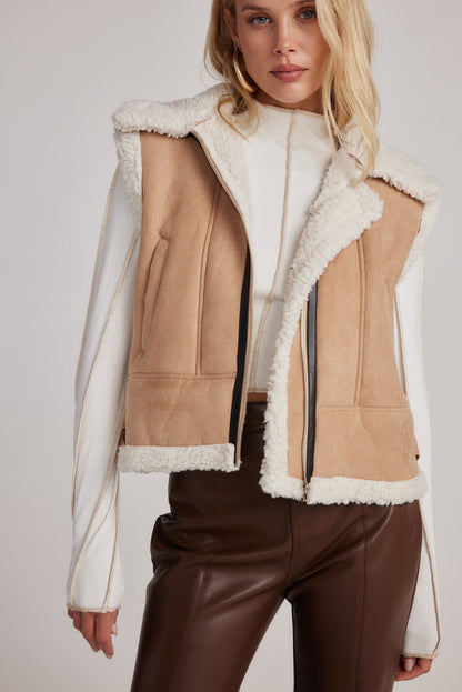 Beige faux suede vest with cream sherpa trim, worn open over white top.