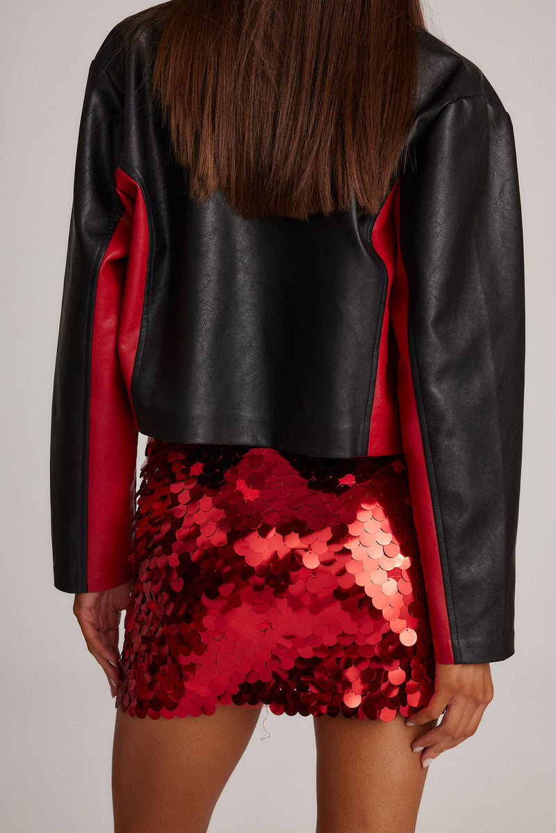 Back view of red disco sequin mini skirt styled with a black cropped leather jacket.