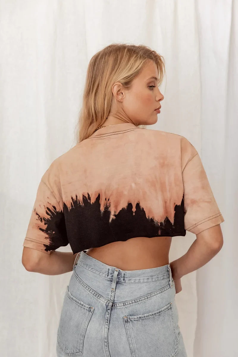 Back view of tan and black tie dye crop tee styled with light denim jeans.