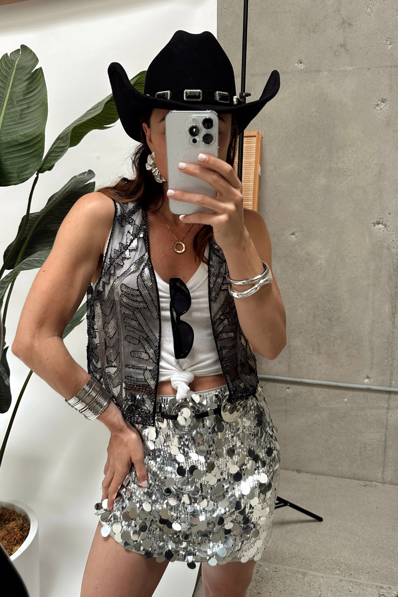 Silver disco sequin mini skirt styled with black cowboy hat and sequin vest for festival.