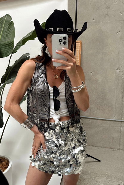 Silver disco sequin mini skirt styled with black cowboy hat and sequin vest for festival.