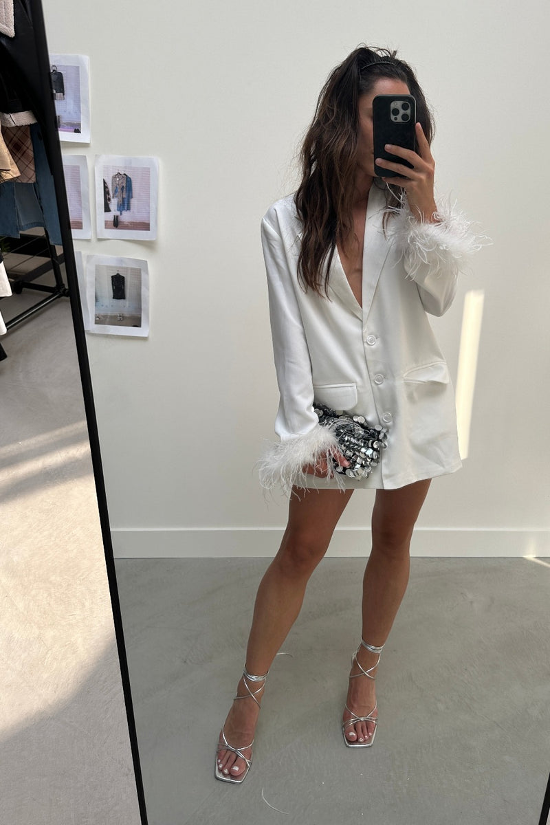 White feather-cuff blazer worn as a dress with silver clutch and heels.